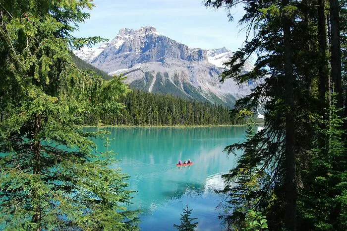 A beautiful blue lake surrounded by mountains and trees, with a small boat, depicting potential misunderstandings locals and foreigners face.