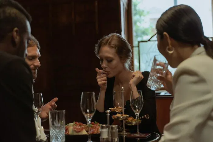 A group of friends, including locals and foreigners, enjoys dinner in a restaurant, a scenario where misunderstandings can arise.
