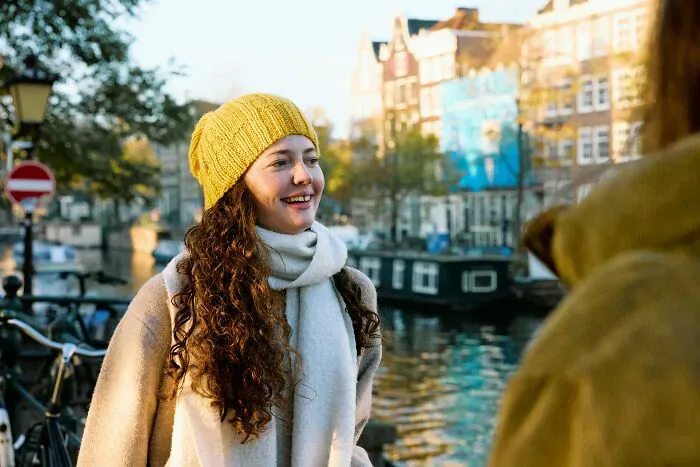A happy foreign woman with long, curly hair smiles widely, avoiding misunderstandings with locals.