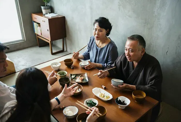 An Asian family eating at a table with chopsticks, demonstrating cultural misunderstandings between locals and foreigners.