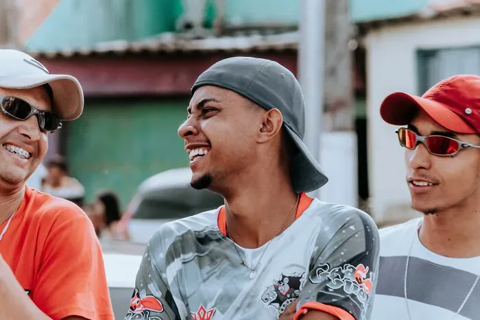 Three smiling young men talking outdoors, highlighting potential misunderstandings between locals and foreigners.